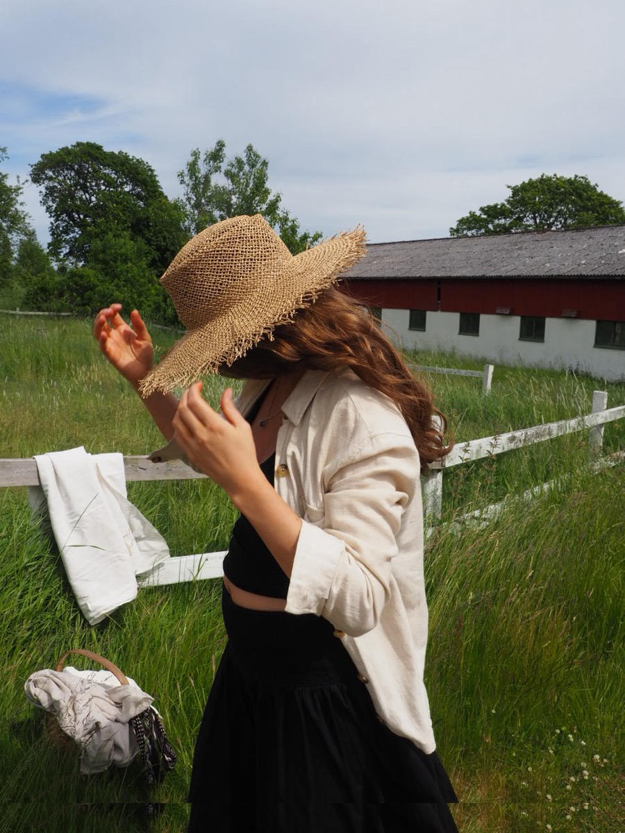 Person i stråhatt och linneskjorta på en sommaräng